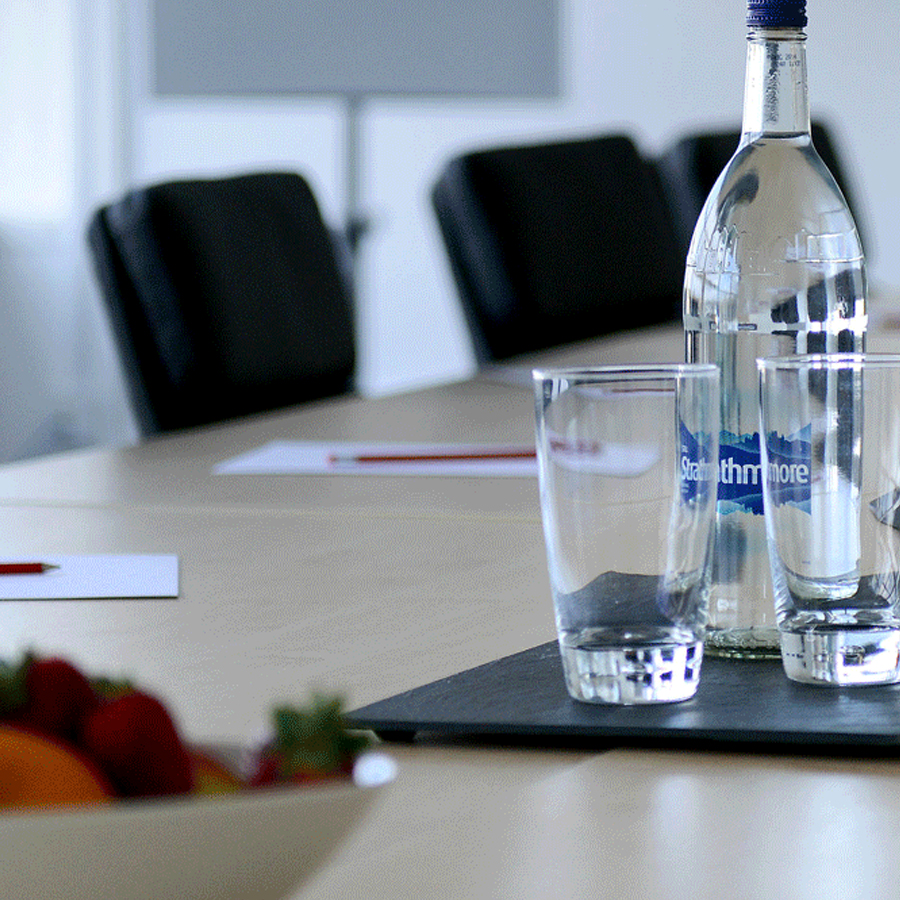 A bottle of water and two glasses on top of a table.