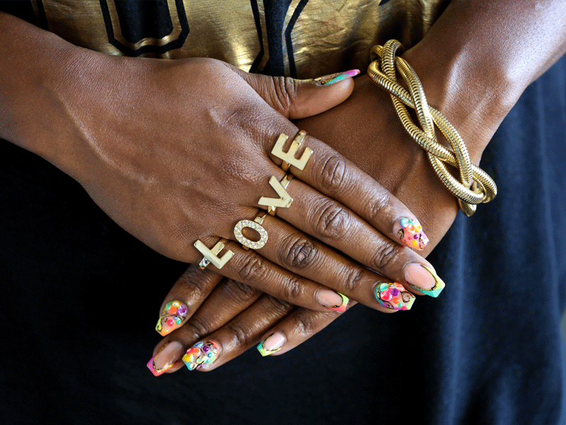 A woman with colorful nails and gold jewelry.